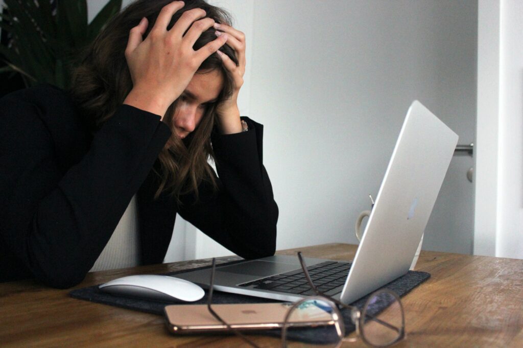 woman with head in hands looking at computer